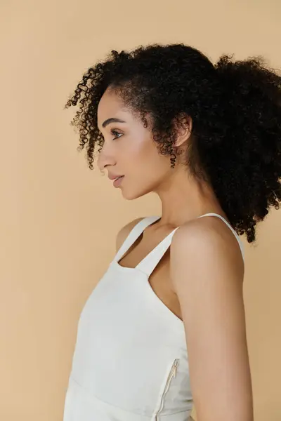 A fashionable woman showcases her chic attire and stunning curls while exuding confidence. — Stock Photo
