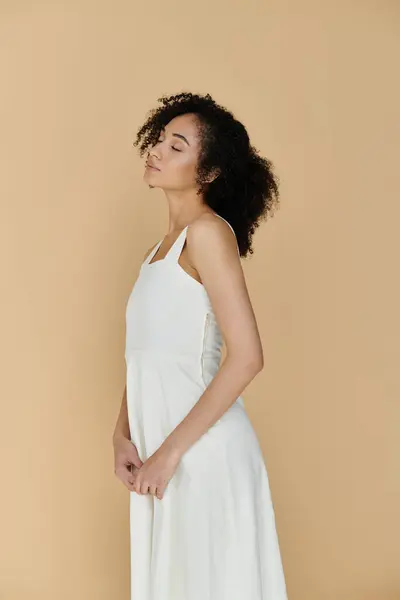 A fashionable woman stands gracefully, showcasing her elegant style in a chic white dress. — Stock Photo