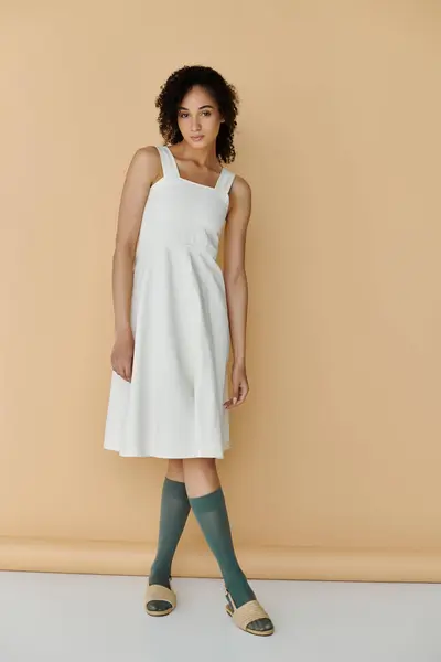 A fashionable woman showcases her chic summer outfit while striking a pose on a neutral background. — Stock Photo