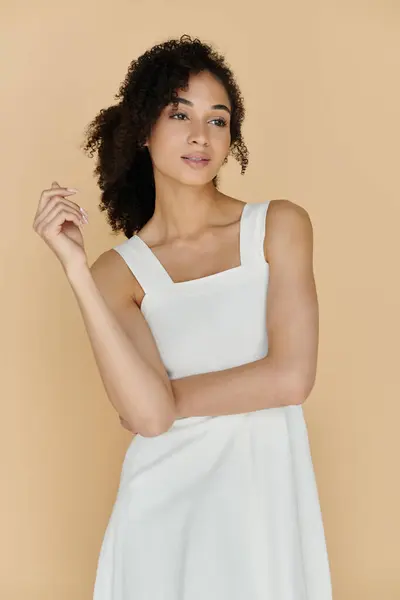 A fashionable woman stands gracefully, showcasing her stylish white dress and natural beauty. — Stock Photo
