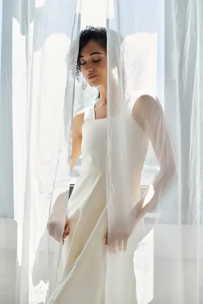 A beautiful woman enjoys the soft light filtering through translucent fabric, showcasing her style. — Stock Photo