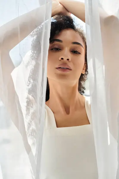 Stylish woman exudes confidence while standing behind delicate fabric in sunlit surroundings. — Stock Photo