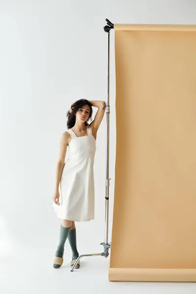 A stylish woman showcases her outfit in a modern studio with soft lighting. — Stock Photo