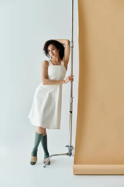 A fashionable woman poses elegantly against a backdrop, showcasing her trendy outfit and confidence. — Stock Photo