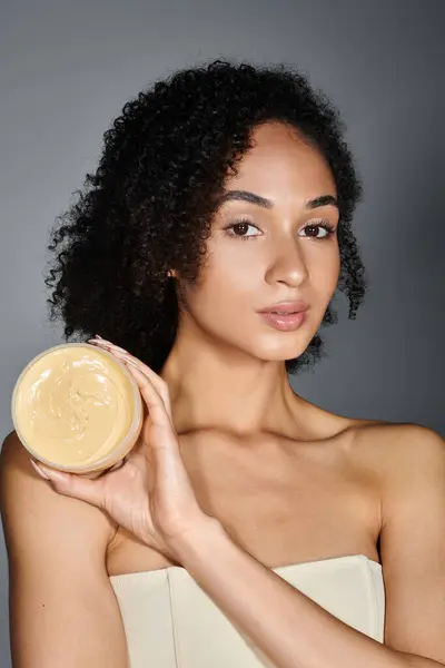 A stylish woman confidently presents her favorite skincare product, highlighting her beauty routine. — Stock Photo