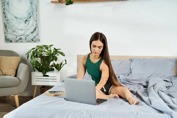 A young woman with short stature relaxes at home, working intently on her laptop while surrounded by comfort. — Stock Photo