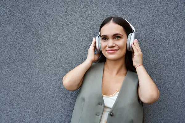 Una giovane donna allegra dai capelli castani ascolta musica all'aperto, abbracciando l'atmosfera calda con un sorriso. — Foto stock
