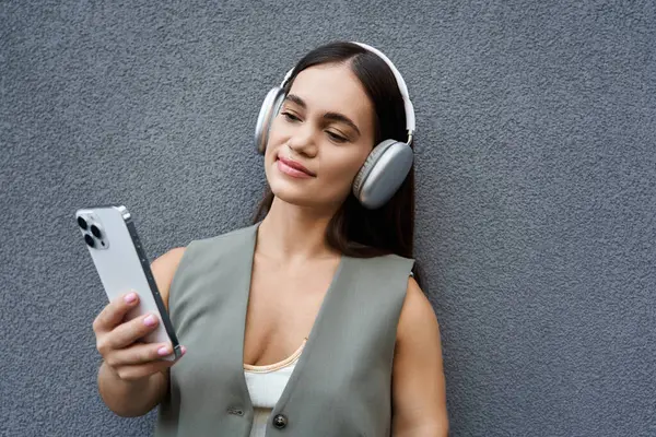 A young brunette woman with a joyful smile listens to music outdoors, fully immersed in her moment of leisure and relaxation. — Stock Photo