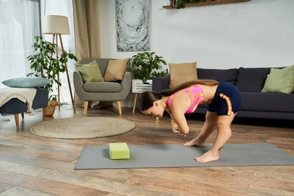 A brunette young woman is exercising at home, focusing on her fitness routine in a beautifully styled living room. — Stock Photo