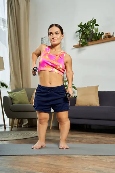 A determined young woman works out in her living room, using dumbbells to build strength and confidence. — Stock Photo