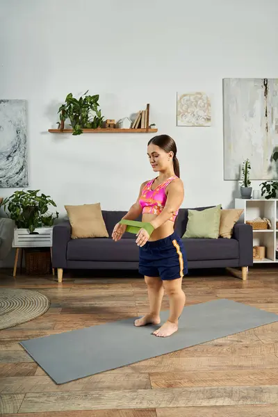 A young brunette woman with a short stature is engaged in an energetic workout at home, focusing on her fitness and health goals. — Stock Photo