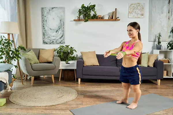 Una giovane donna bruna con una bassa statura si sta impegnando in una routine di allenamento a casa, circondata da piante e un'atmosfera accogliente. — Foto stock