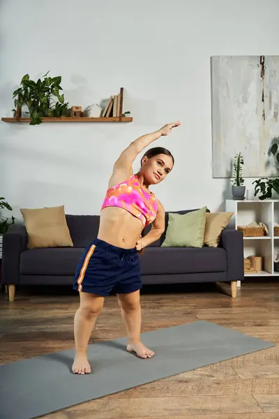 A determined brunette woman with a short stature stretches at home, showcasing her commitment to fitness and well-being. — Stock Photo