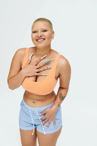 A young bald woman confidently expresses joy while wearing a colorful ensemble. — Stock Photo