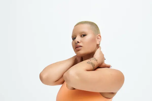 A young woman with a shaved head poses with grace, celebrating her vibrant fashion choice. — Stock Photo