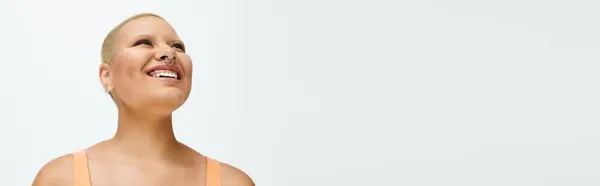 A young woman with a bald head radiates happiness while wearing colorful clothing. — Stock Photo
