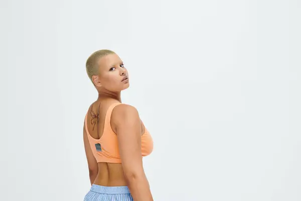 A young bald woman showcases vibrant fashion while exuding confidence and strength. — Stock Photo