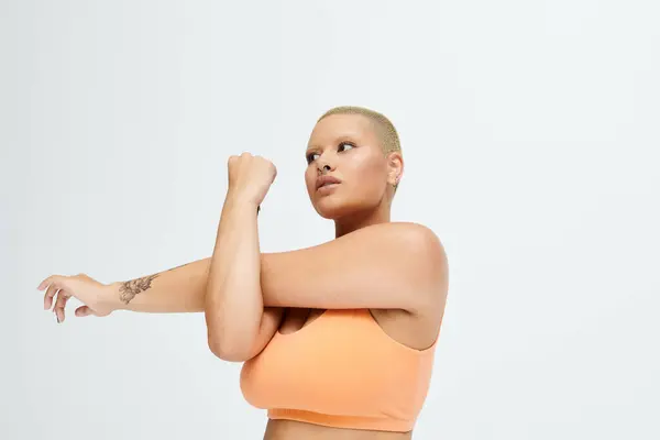 A young bald woman dressed in vibrant colors extends her arm, embodying strength and elegance. — Stock Photo