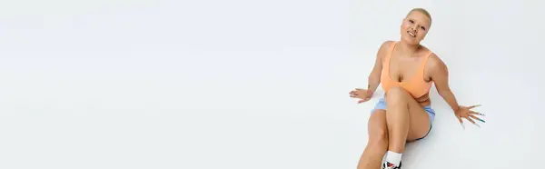 A joyful bald woman in bright clothes sits against a simple backdrop. — Stock Photo