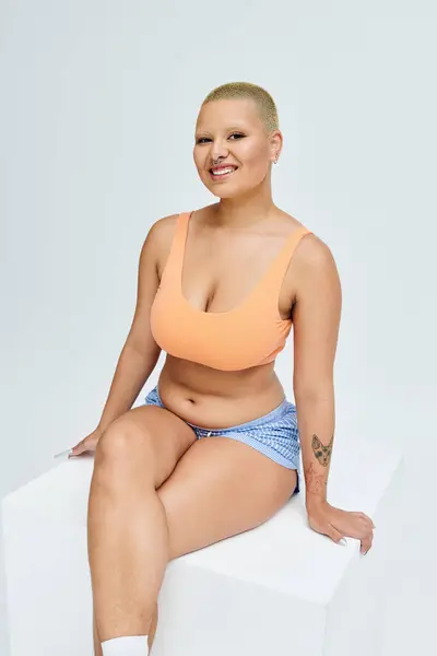 A young bald woman exudes confidence in colorful clothing while posing gracefully. — Stock Photo
