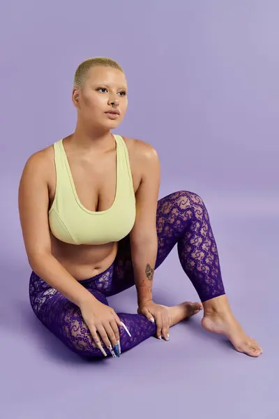 A young bald woman showcases her colorful outfit while sitting elegantly in a serene setting. — Stock Photo