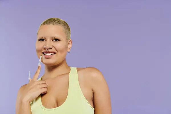 Una joven calva vestida con colores vibrantes muestra su confianza mientras posa juguetonamente. - foto de stock