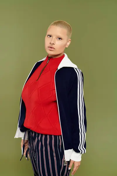 A young bald woman dressed in vibrant attire stands confidently with a bold expression. — Stock Photo