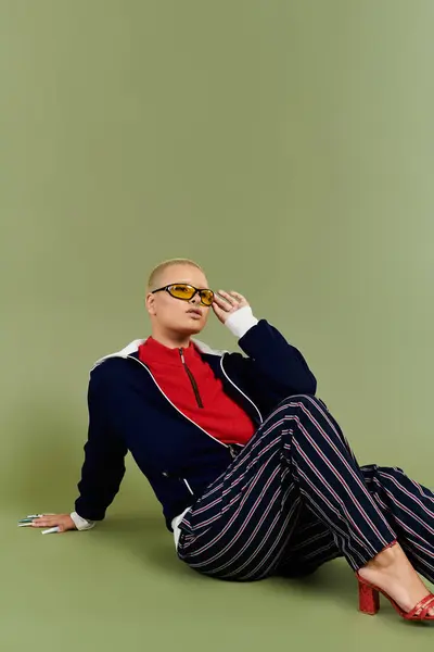 La joven calva se sienta casualmente en el suelo, exudando confianza en su atrevido y colorido atuendo. — Stock Photo