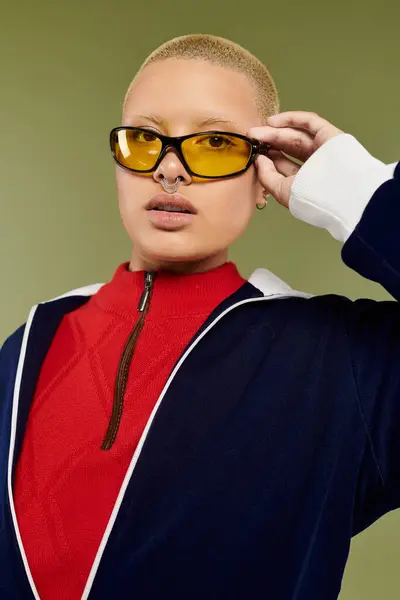 Eine junge Frau mit Glatze präsentiert ihre lebendige Mode, während sie selbstbewusst mit kühner Sonnenbrille posiert. — Stockfoto