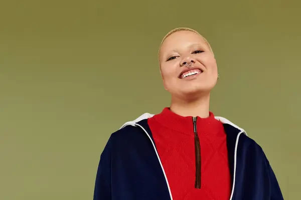 A cheerful young bald woman radiates confidence in her colorful outfit, smiling beautifully. — Stock Photo
