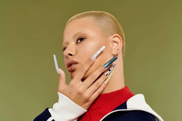 A confident bald woman poses with flair, highlighting her colorful outfit and elaborate nails. — Stock Photo