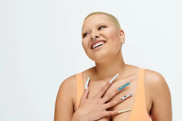 A young bald woman dressed in colorful attire radiates joy in a bright studio atmosphere. — Stock Photo