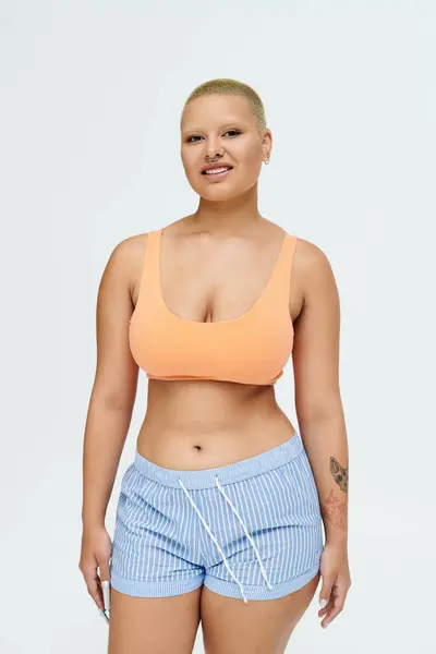 Smiling with warmth, a young bald woman showcases her vibrant outfit and joyful spirit. — Stock Photo