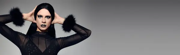 A fashionable gender fluid person showcases bold makeup and a stylish black ensemble in a studio setting. — Stock Photo