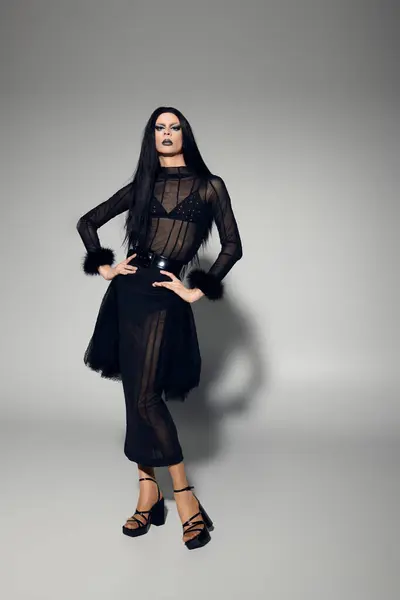 A fashionable drag queen exudes confidence in a stylish black outfit, striking a pose in a studio setting. — Stock Photo