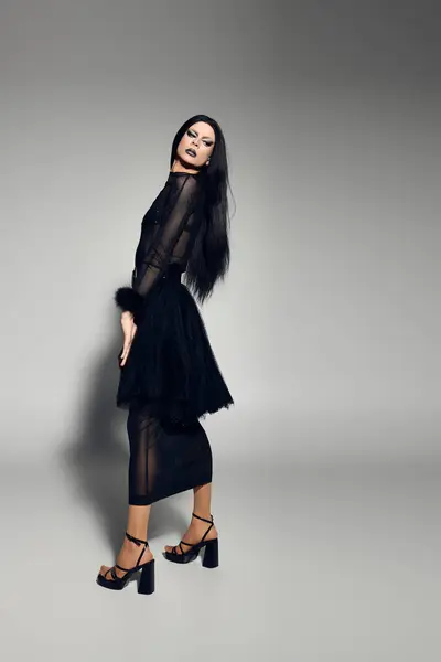 This stylish person embodies confidence with their striking black attire, accentuated by a striking backdrop. — Stock Photo