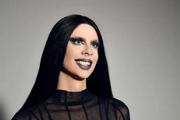 This stylish individual radiates confidence in a sleek black outfit against a grey backdrop, exuding elegance. — Stock Photo