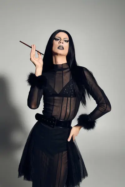 A fashionable drag queen showcases bold style and attitude in a sleek black ensemble set in a studio. — Stock Photo