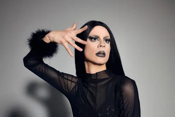 Un artiste drag captivant met en valeur leur sens de la mode audacieux dans une tenue noire élégante avec un flair dramatique. — Photo de stock