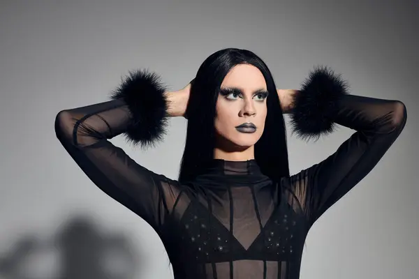 Una drag queen de moda alcanza una pose poderosa, mostrando un impresionante atuendo negro en un elegante estudio. — Stock Photo