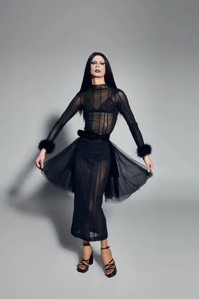 A fashionable drag queen exudes confidence in a striking black outfit against a sleek grey backdrop. — Stock Photo