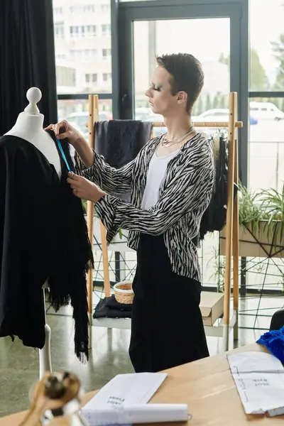In a vibrant studio, a gender fluid fashion designer meticulously tailors a garment on a dressmaker's dummy. — Stock Photo