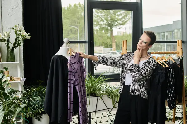 A stylish designer explores fabric choices while surrounded by lush plants and artistic clothing displays. — Stock Photo