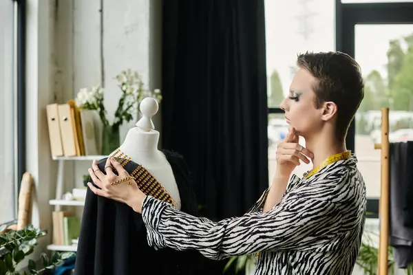 Ein talentierter Modedesigner passt in seinem schicken Atelier ein Kleidungsstück sorgfältig an, umgeben von künstlerischen Elementen. — Stockfoto