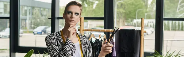 A stylish transgender fashion designer is creating innovative designs in a vibrant studio space. — Stock Photo