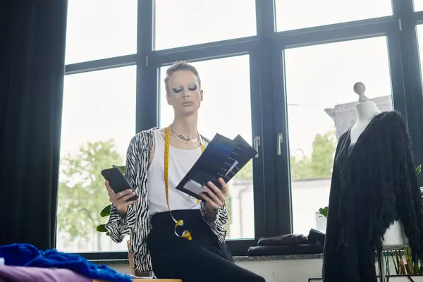 A creative fashion designer explores innovative ideas while balancing design sketches and a smartphone. — Stock Photo
