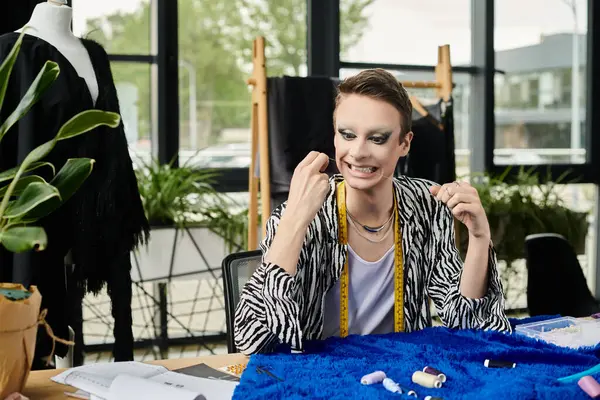 Un diseñador de moda fluido de género talentoso trabaja alegremente en telas coloridas en un estudio aireado. — Stock Photo