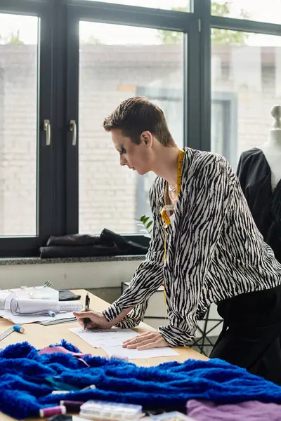 A fashion designer immersed in creativity, drafting designs in a vibrant, contemporary studio space. — Stock Photo