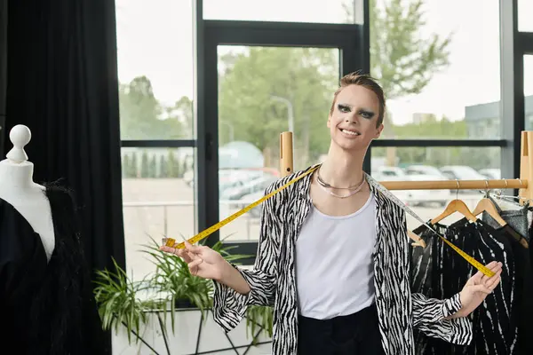 A stylish gender fluid fashion designer works on designs, surrounded by chic clothing in their studio. — Stock Photo