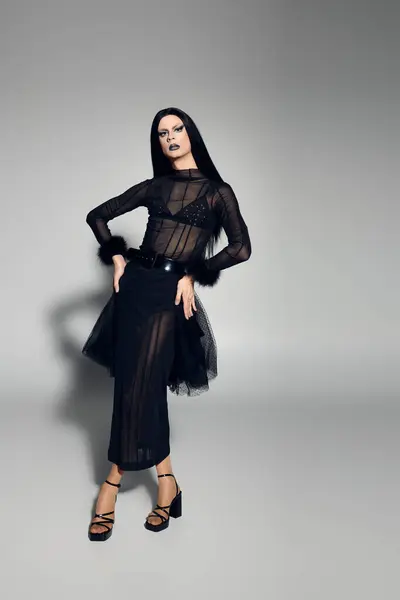 This fashionable performer exudes confidence while posing in a chic black ensemble against a muted backdrop. — Stock Photo